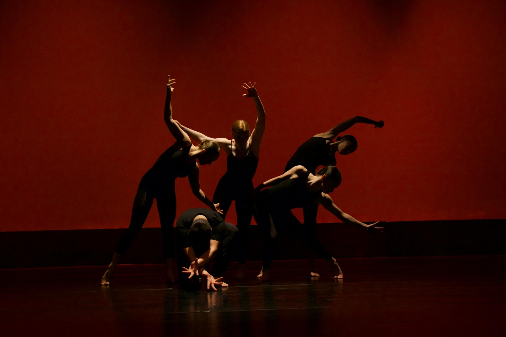 Groupe de danseurs sur scène devant un fond rouge